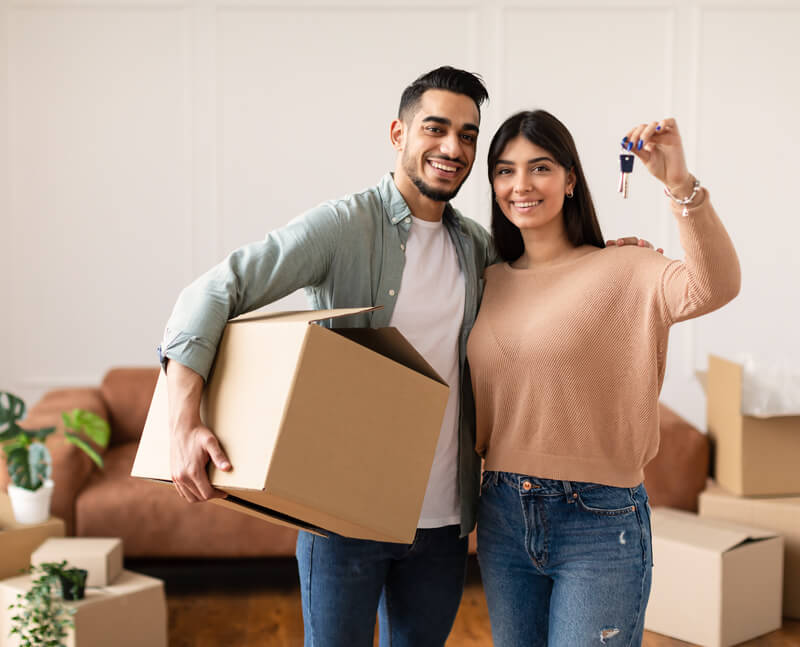 couple moving in holding boxes and keys